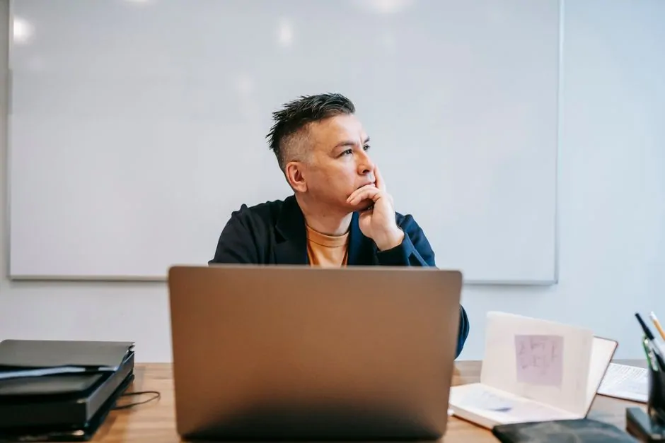 Business owner at a desk looks at his laptop, searching for an available domain name