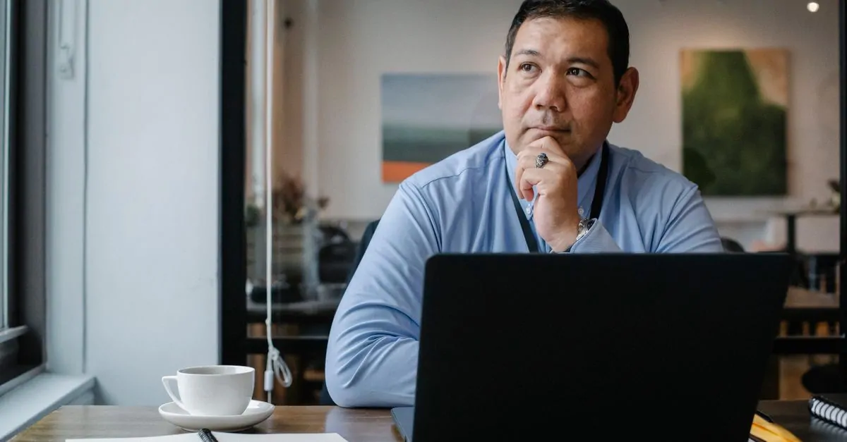 Business owner at a desk looks at his laptop, searching for an available domain name